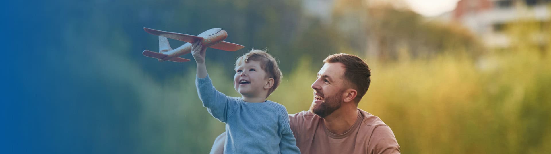 Father and son playing in park with toy airplane